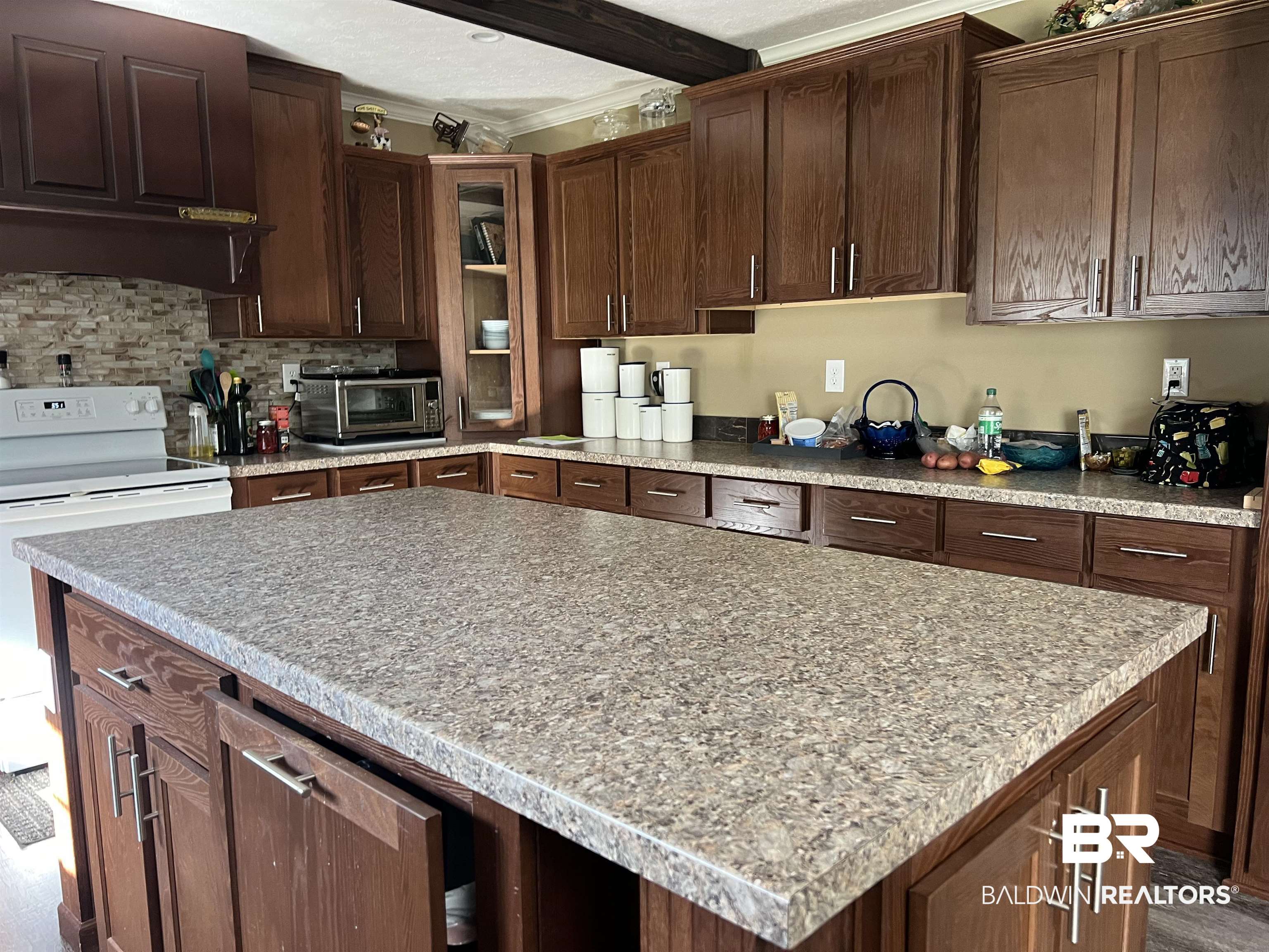 16824 Underwood Road Foley, AL 36535 - Photo 8 of 25 Kitchen with dark brown cabinetry, ornamental molding, backsplash, hardwood / wood-style flooring, and a center island