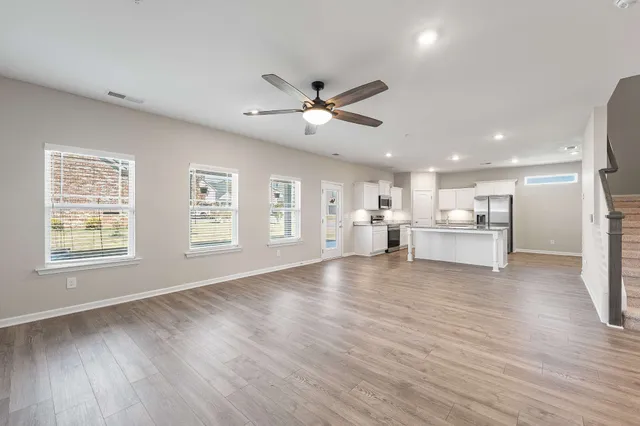 a view of an empty room with a kitchen and wooden floor
