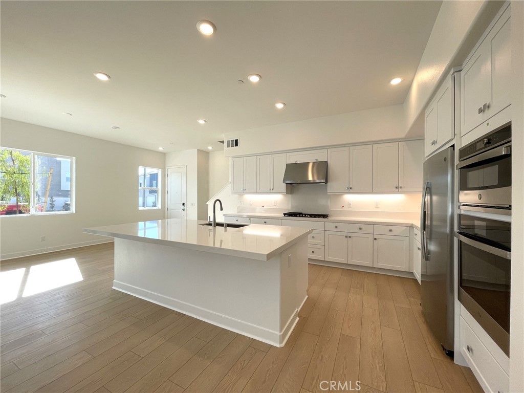 141 Baluster Irvine, CA 92618 - Photo 12 of 40 a large kitchen with cabinets wooden floor and stainless steel appliances