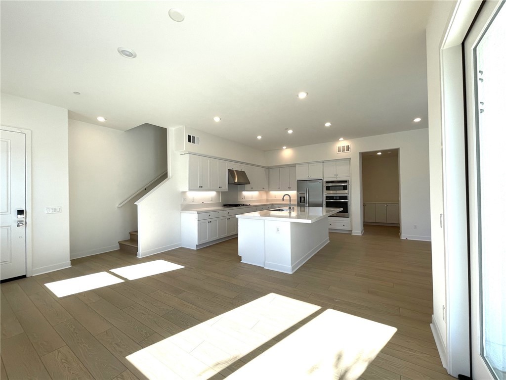 141 Baluster Irvine, CA 92618 - Photo 7 of 40 a living room with stainless steel appliances kitchen island granite countertop a refrigerator a sink a stove and white cabinets with wooden floor