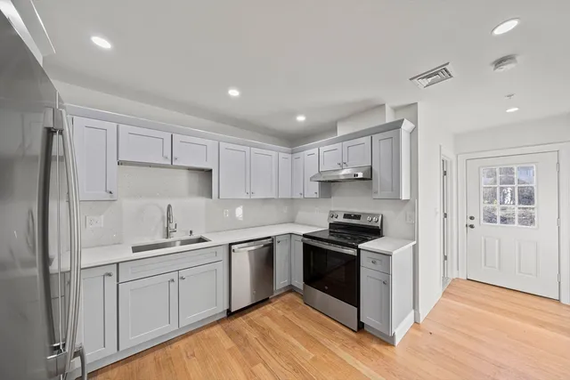 a kitchen with stainless steel appliances granite countertop a sink stove and refrigerator