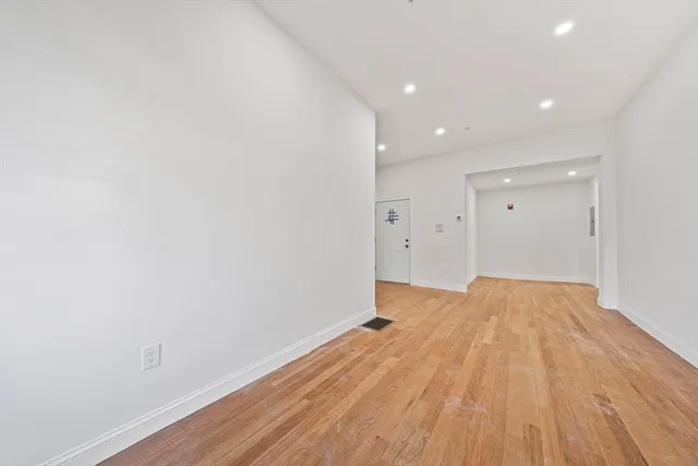 a view of empty room with wooden floor and entryway
