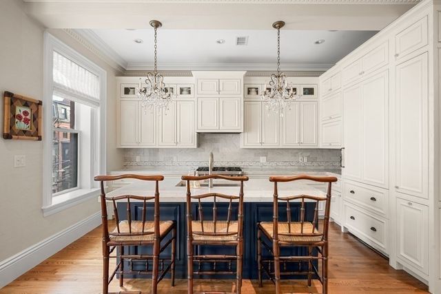 a kitchen with stainless steel appliances granite countertop a dining table chairs and white cabinets