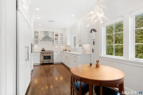 a kitchen with stainless steel appliances a sink a stove a refrigerator dining table and chairs