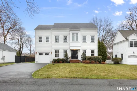 a front view of a house with a yard outdoor seating and covered with trees