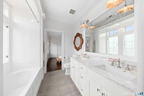 a en suite bathroom with a granite countertop sink and a large mirror