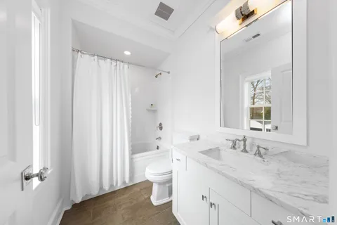 a bathroom with a granite countertop sink a toilet and shower