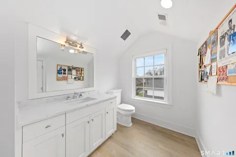 a spacious bathroom with 2 sink toilet a mirror and a window