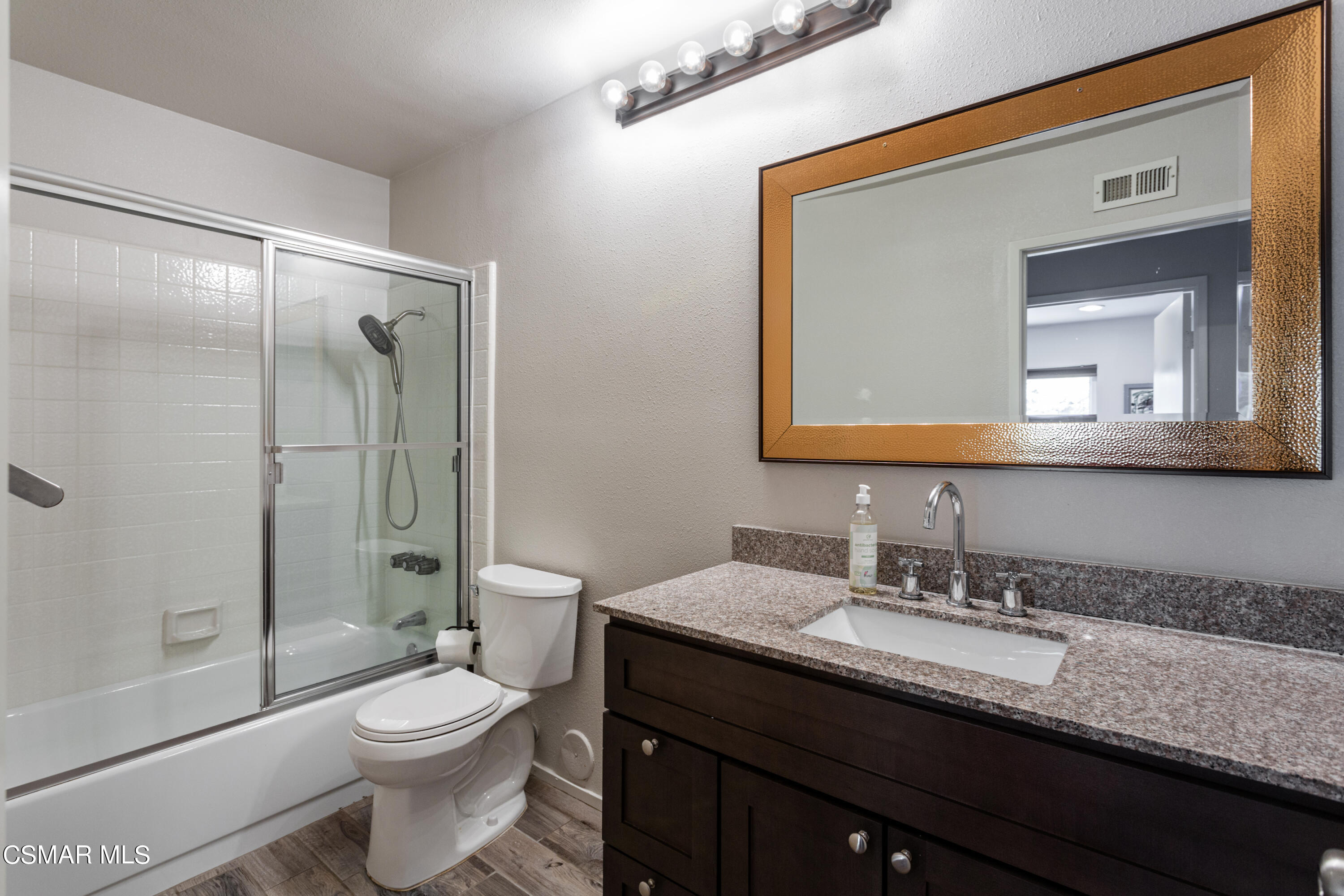 4249 Laurelhurst Road Moorpark, CA 93021 - Photo 20 of 30 a bathroom with a granite countertop toilet sink a mirror a bathtub and shower