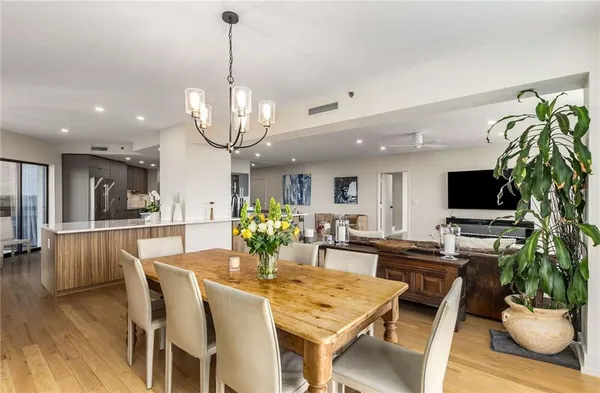 a large white kitchen with kitchen island a sink a counter top space and stainless steel appliances