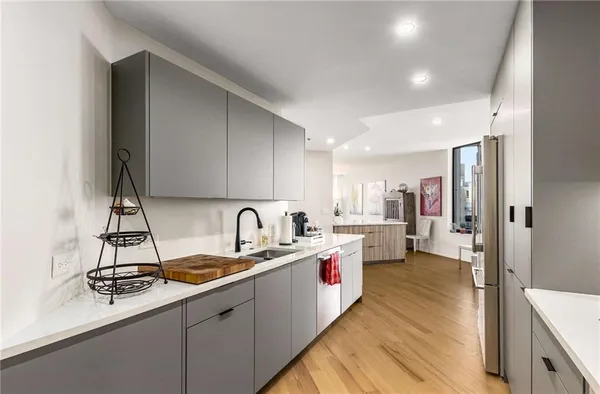 a bedroom with a bed a large window and walk in closet with wooden floor