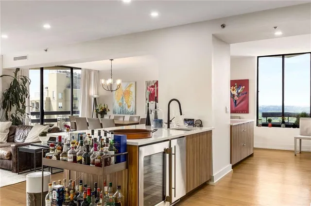 a large kitchen with stainless steel appliances a sink dishwasher a stove a dining table and chairs with wooden floor