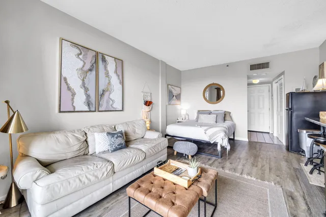 a living room with furniture a flat screen tv and kitchen view