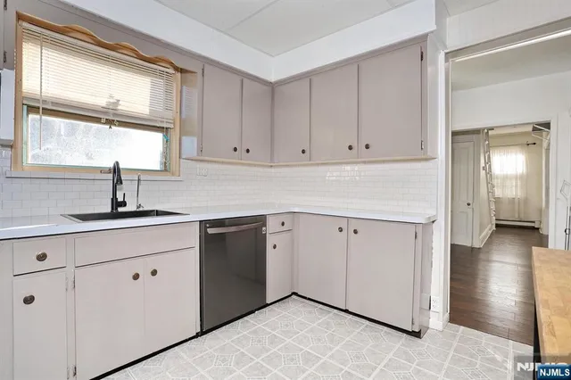 a kitchen with white cabinets and a window