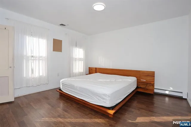 a bed sitting in a spacious bedroom next to a window and wooden floor