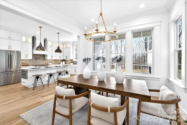 a dining room with wooden floor a chandelier a wooden table and chairs