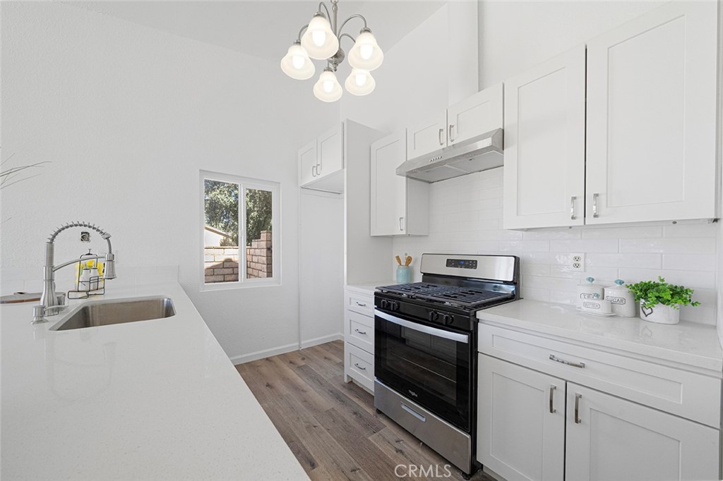 917 Renee Street Redlands, CA 92374 - Photo 14 of 26 Open galley style kitchen that has been thoughtfully reimagined to accommodate today's styles and needs. Room for a refrigerator at the corner by the window. Newer stove, hood, sink, dishwasher, fixtures, subway tile, soft close cabinets and drawers.