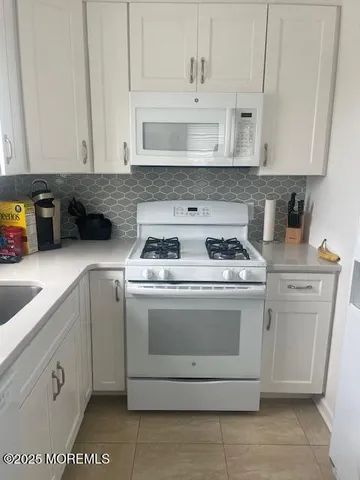 a kitchen with white cabinets and white appliances