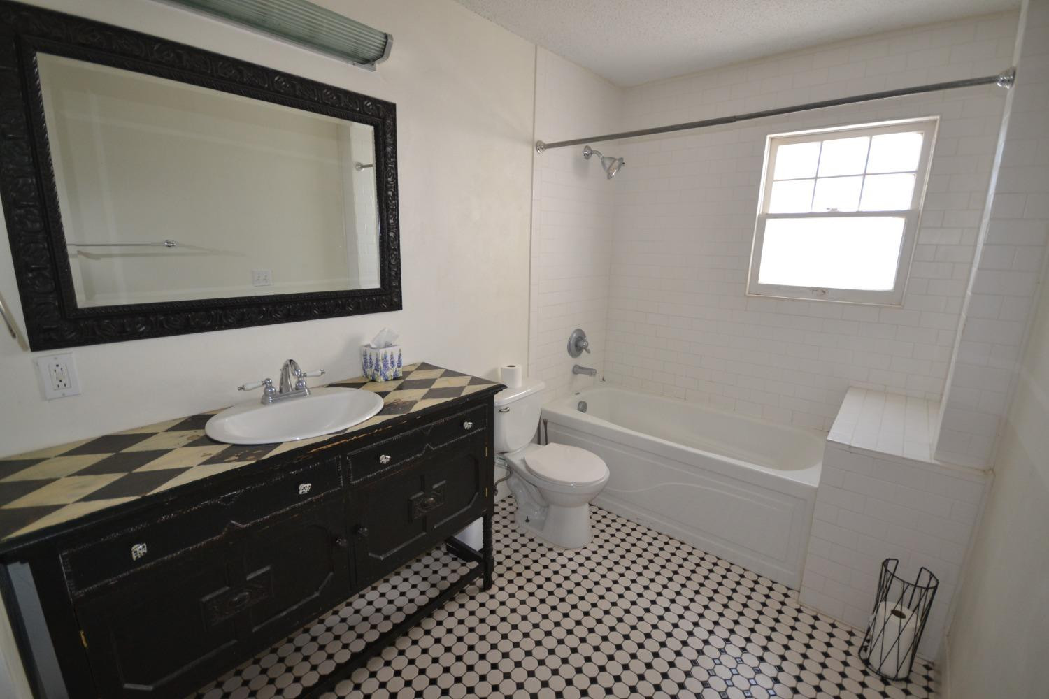 2611 31st Street Lubbock, TX 79410 - Photo 12 of 15 a bathroom with a granite countertop sink toilet a mirror and a shower