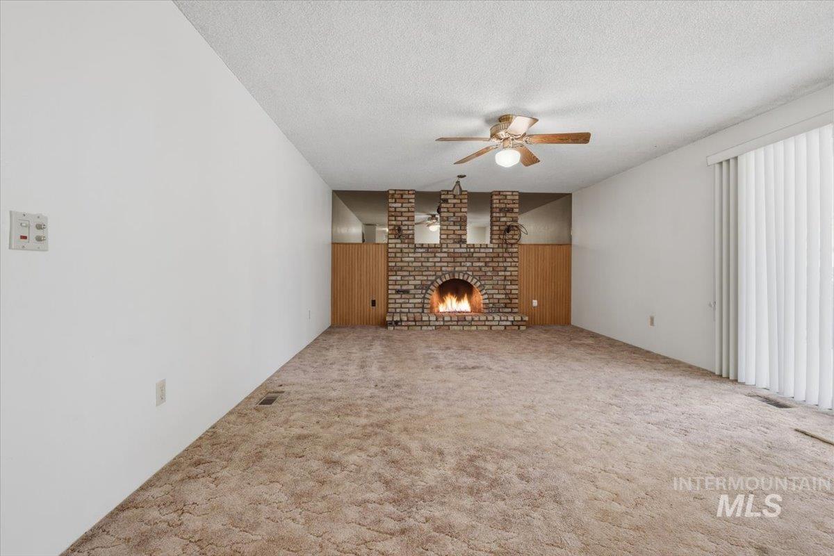 1311 North Middleton Road Nampa, ID 83651 - Photo 39 of 49 Brick fireplace with hearth, wood paneling, and ceiling fan