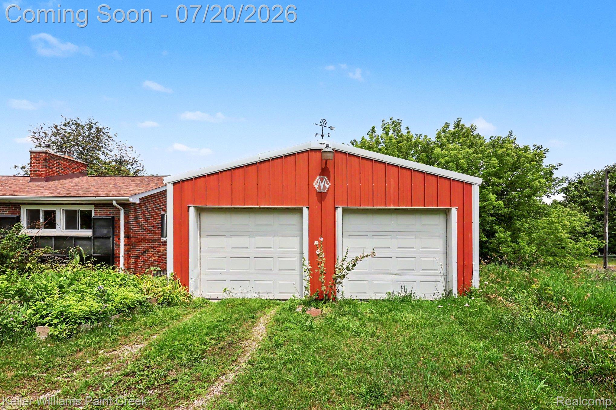 1371 East Leonard Road Leonard, MI 48367 - Photo 22 of 32 Red metal utility building featuring two white garage doors, a sloped roof, and a rooftop weather vane