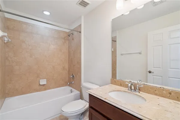 a bathroom with a granite countertop bathtub shower sink vanity mirror and toilet