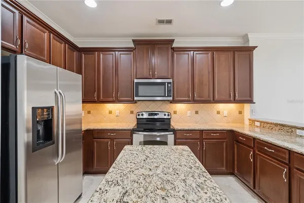 a kitchen with stainless steel appliances granite countertop a refrigerator stove and sink