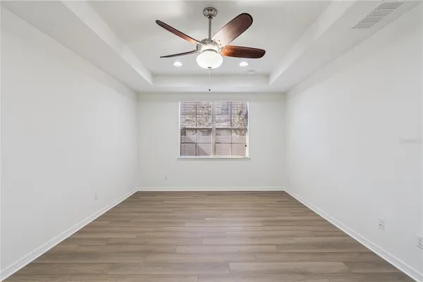 an empty room with wooden floor and ceiling fan