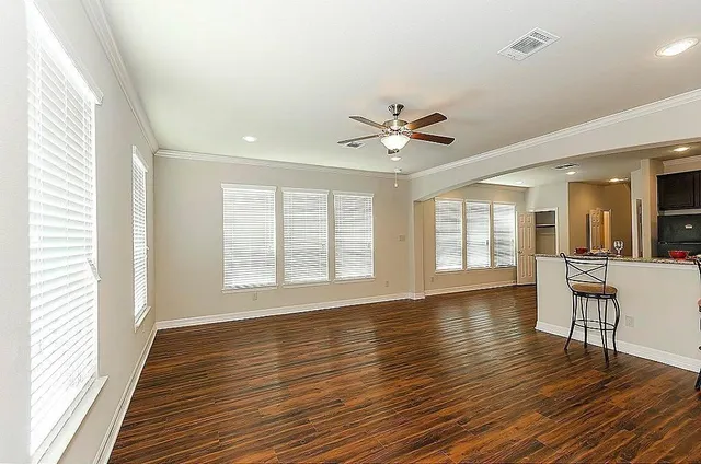 a view of an empty room with wooden floor and a window