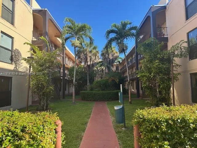 a view of a yard with plants and large trees