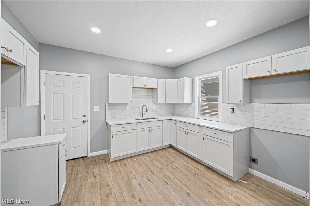 3925 Riverside Avenue Cleveland, OH 44109 - Photo 11 of 48 Kitchen featuring white shaker-style cabinetry, light wood-finish flooring, recessed lighting, white subway tile backsplash, and light-toned countertops