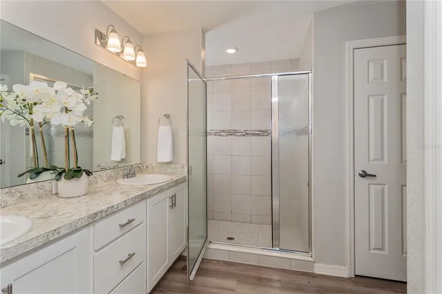 a bathroom with a granite countertop sink two mirror and shower