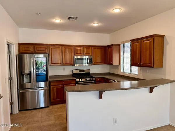 a kitchen with stainless steel appliances granite countertop a refrigerator a sink and a stove