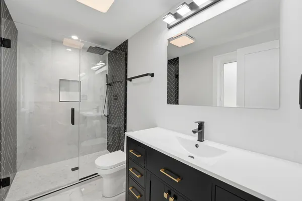 a bathroom with a sink a toilet a mirror and shower