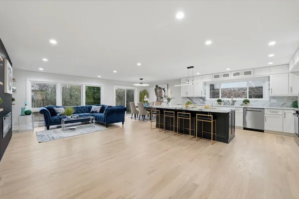 a living room with stainless steel appliances furniture and a kitchen view