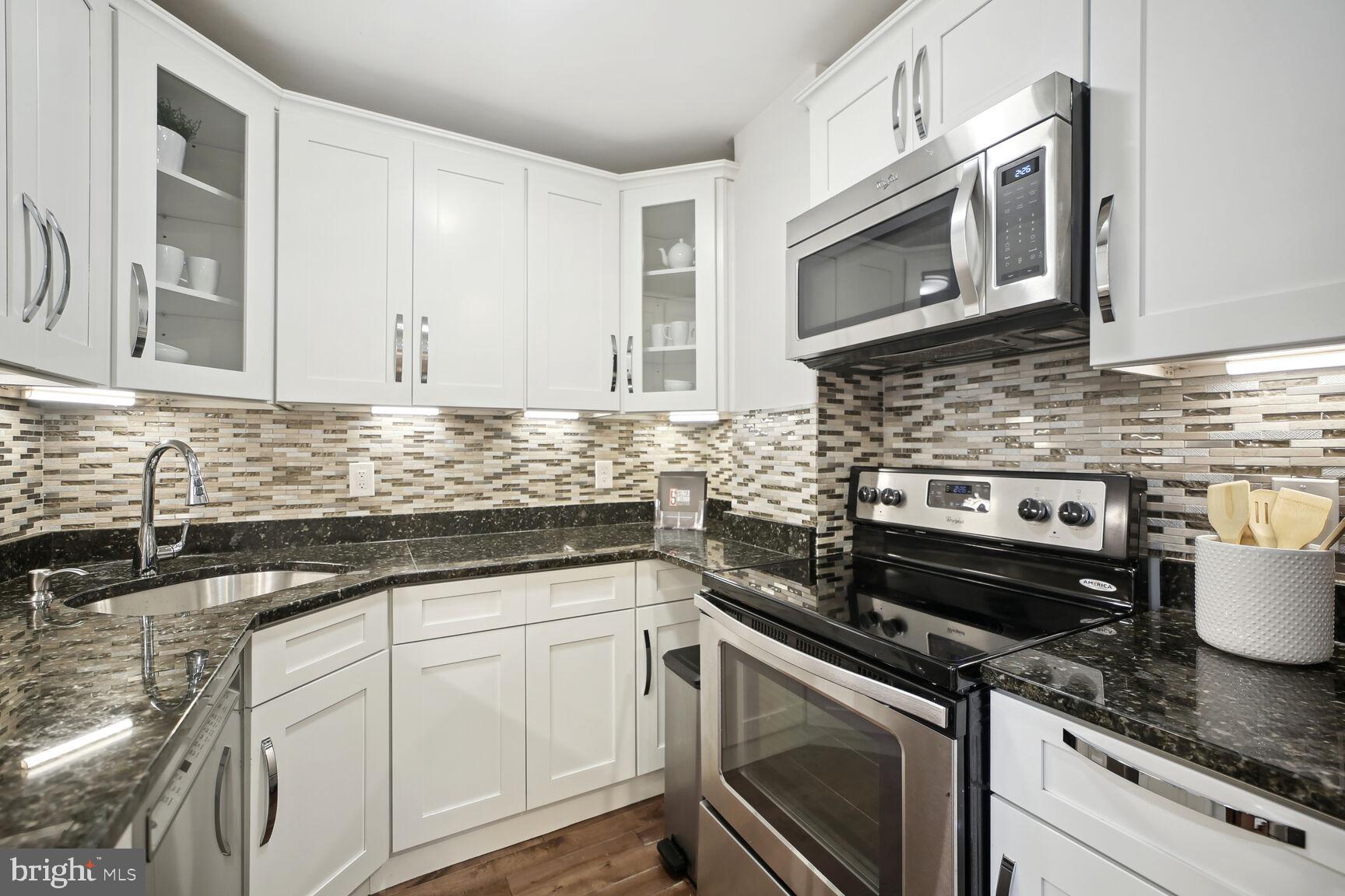 1451 Park Road Northwest, Unit 113 Washington, DC 20010 - Photo 14 of 50 a kitchen with granite countertop white cabinets stainless steel appliances and a sink