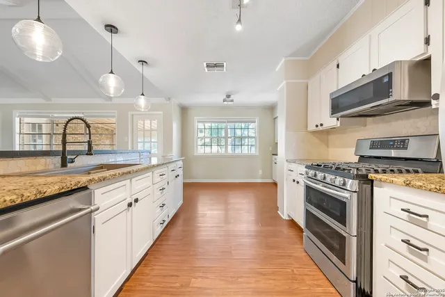 a large kitchen with granite countertop a stove and a sink