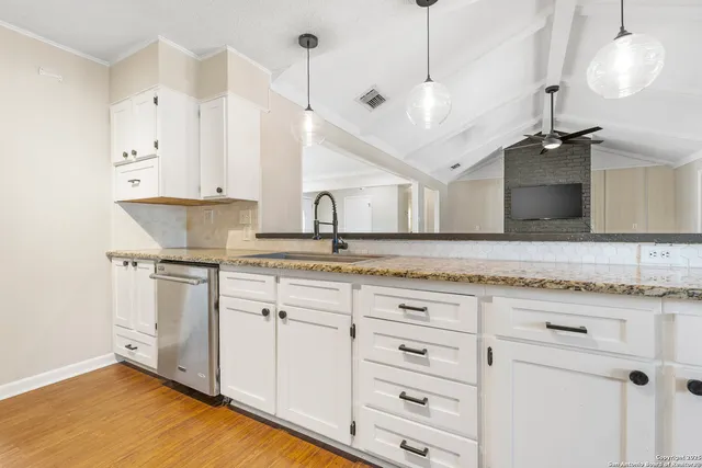 a kitchen with kitchen island granite countertop a sink cabinets and stainless steel appliances