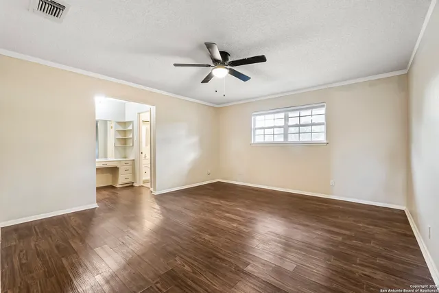 an empty room with wooden floor ceiling fan and windows