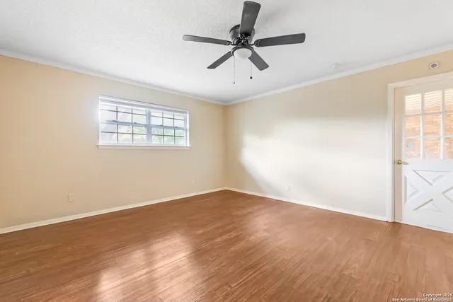 an empty room with wooden floor fan and windows