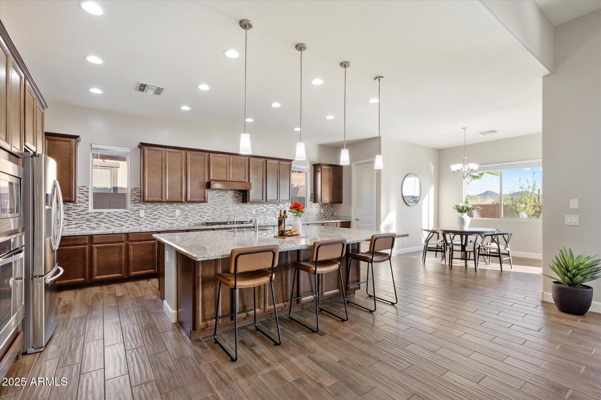 9275 West Plum Road Peoria, AZ 85383 - Photo 8 of 39 a large kitchen with lots of counter space a sink and chairs