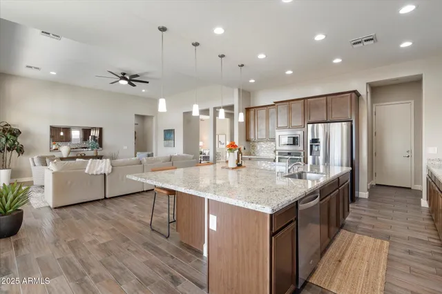 a large kitchen with kitchen island a stove a sink a refrigerator and a dining table with wooden floor