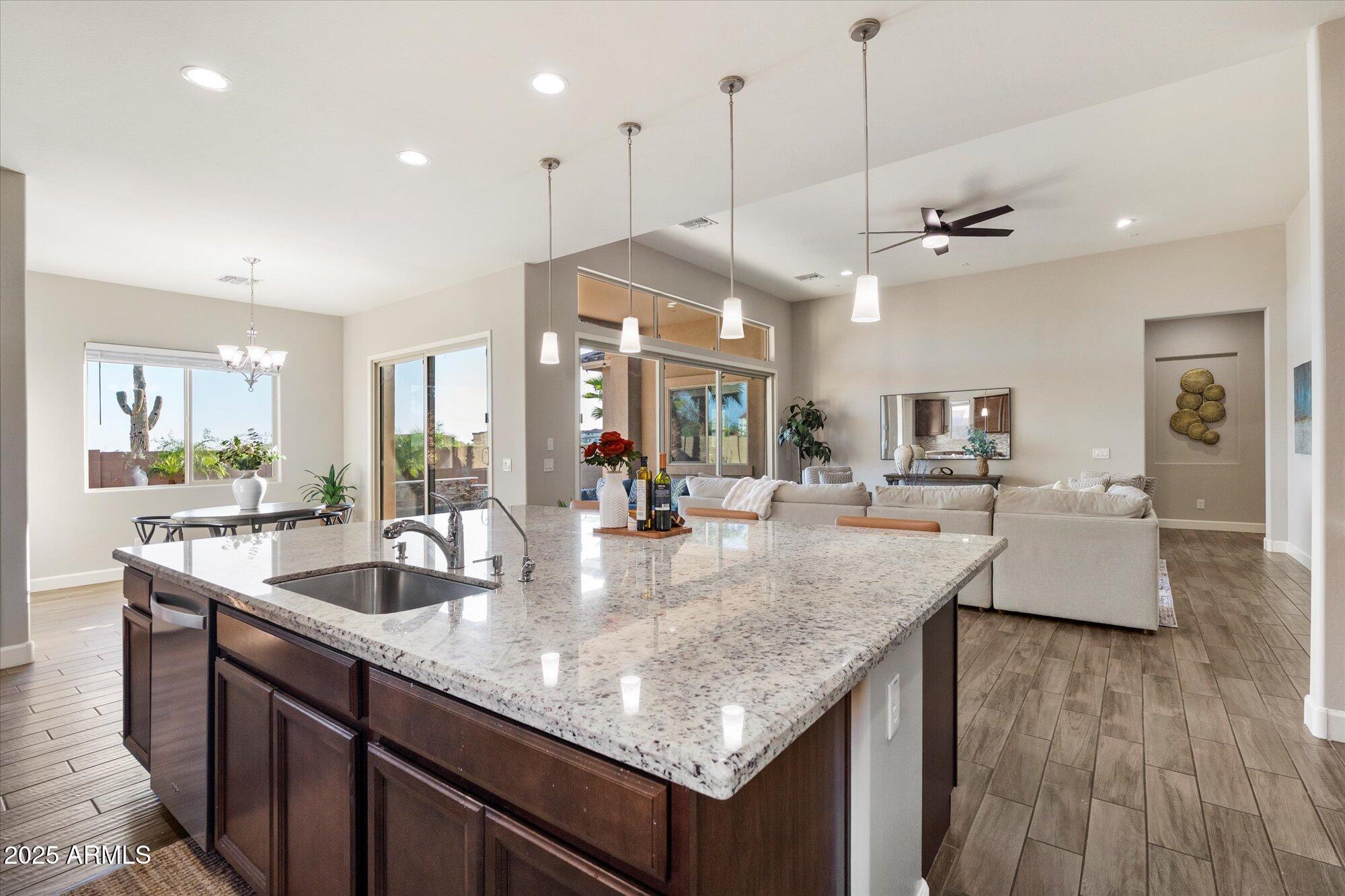 9275 West Plum Road Peoria, AZ 85383 - Photo 10 of 39 a kitchen with granite countertop kitchen island a counter space a sink and living room view