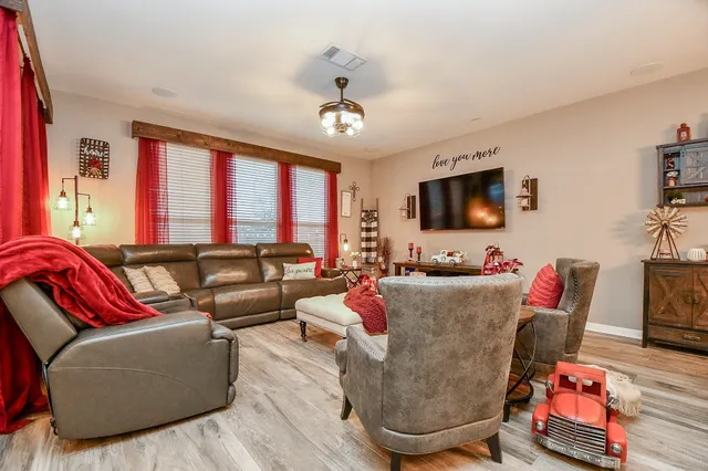 a living room with furniture a flat screen tv and a window