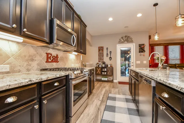a kitchen with stainless steel appliances granite countertop a sink stove and refrigerator