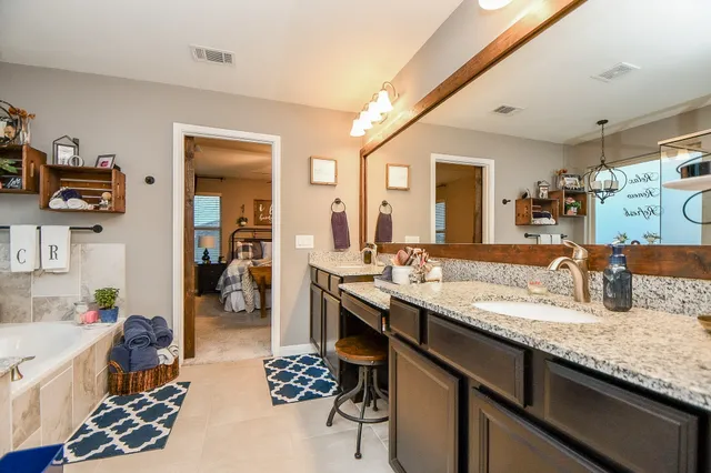 a en suite bathroom with a granite countertop sink and a mirror