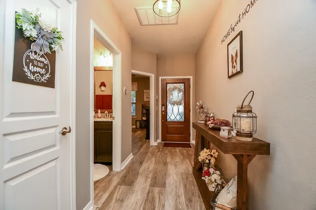 a view of a hallway with wooden floor and a chandelier