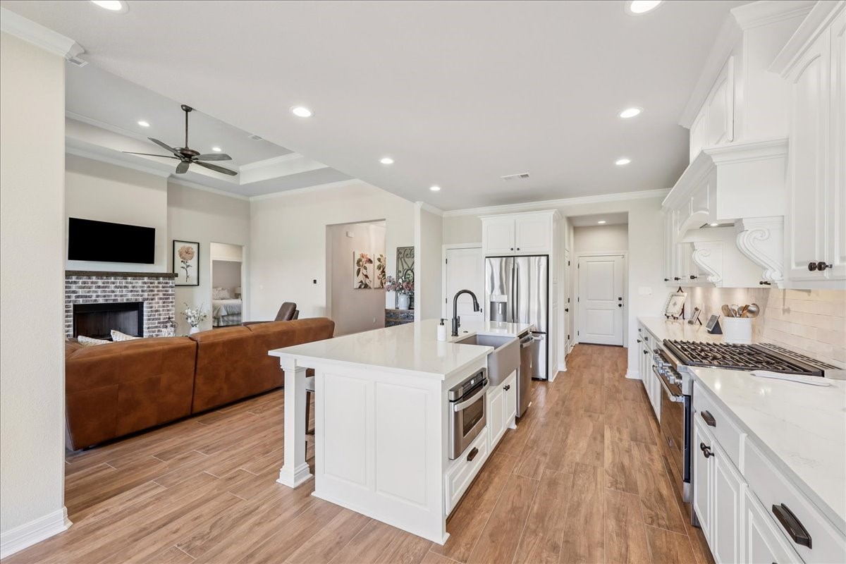 9205 Chicory Street Beaumont, TX 77713 - Photo 5 of 43 a large white kitchen with stainless steel appliances granite countertop a stove oven a refrigerator a oven with a dining table and chairs with wooden floor