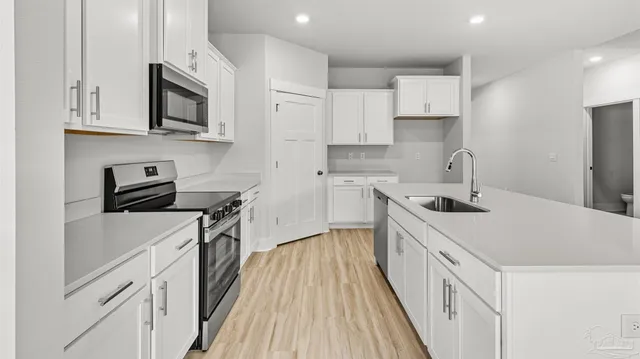 a kitchen with stainless steel appliances a sink stove and white cabinets