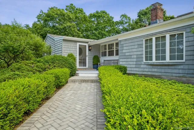 a front view of a house with a yard and potted plants